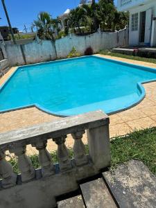 ein großer blauer Pool mit einer Bank daneben in der Unterkunft Residences Les Loisirs in Grand Baie