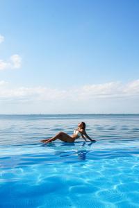 a woman laying on the water in the ocean at Casa Tortugas Boutique Hotel - A Hidden Gem in Cancun in Cancún