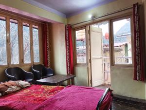 奈尼塔尔JK Guest House的卧室配有床、桌子和窗户。