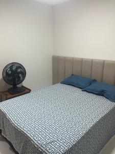 1 dormitorio con 1 cama con almohada azul y ventilador en Apartamento Pérola do Mar, en Ilhéus