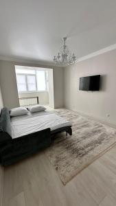une chambre avec un grand lit et une télévision à écran plat dans l'établissement Apartment, à Aqtöbe