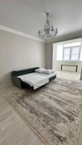 une chambre avec un lit avec un tapis et un lustre dans l'établissement Apartment, à Aqtöbe