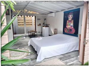 a bedroom with a white bed and a painting on the wall at Un ptit coin de bonheur in Cul de Sac