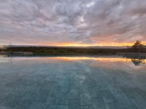 an empty swimming pool with a sunset in the background at Bellamontagna Suites in Mina Clavero
