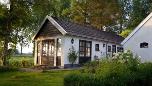 Ce petit cottage blanc dispose d'un toit noir. dans l'établissement B&B Droom 44, à Buinerveen
