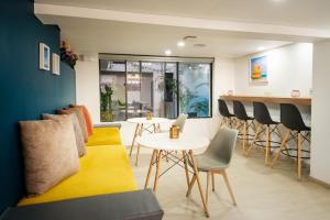 un soggiorno con divano giallo, tavoli e sedie di Palermo Home Bogota & Art Gallery a Bogotá