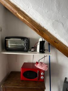 a red microwave and a toaster oven on a shelf at AZAHAR in Lecrin