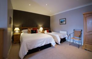 um quarto de hotel com duas camas e uma cadeira em The Park Guest House, Stornoway em Stornoway