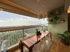 a dining room with a wooden table and a large window at iFlat Winner Sport Life Jardim Goiás in Goiânia