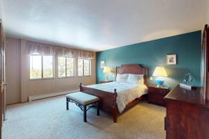 a bedroom with a bed and a chair and windows at House on Cold Creek in South Lake Tahoe