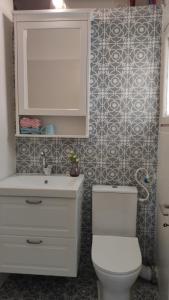 a bathroom with a white toilet and a sink at Stylish Quiet and Central in Rechovot +14 photos