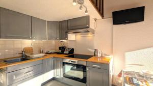 a kitchen with gray cabinets and a sink and a stove at Résidence Les Anémones - Agréable T2 en duplex avec balcon 4 personnes MAE-6861 in Vallouise +1 photo