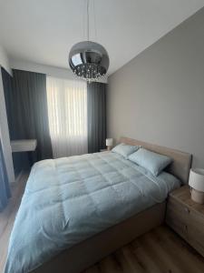 a bedroom with a large bed and a chandelier at Amelie's Apartment 2 in Skopje