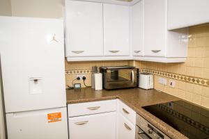 a kitchen with white cabinets and a microwave at Greatmindz abode in Kingshurst