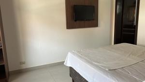 a bedroom with a bed and a tv on the wall at Apartamento na praia in Torres