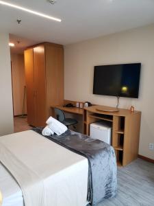 una camera d'albergo con un letto e una scrivania con una televisione di Flat 811 - Hotel Comfort Taguatinga a Brasilia