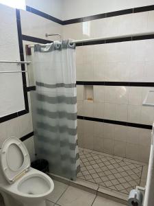a bathroom with a shower curtain and a toilet at Hotel Albatros Palace - Bungalow G in Manzanillo +16 photos