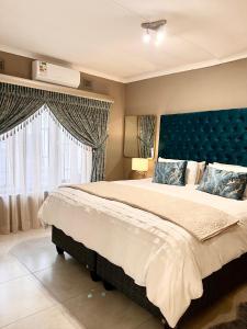 a bedroom with a large bed with a blue headboard at Pistachio villa in Durban