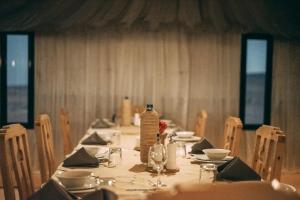 a long dining table with a bottle of water on it at Antares Desert Camp in Merzouga +21 photos