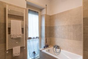 baño con bañera, lavabo y ventana en La Casa di Emma a Trastevere en Roma