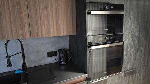 a kitchen with a stove and a microwave at Apartament Dark Prestige NEW ! - dostęp 24h, PROJEKTOR , garaż podziemny , klimatyzacja , duży taras in Kielce +34 photos