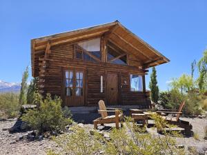 a log cabin with two benches in front of it at Cabañas Isidris Uspallata in Uspallata