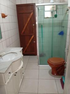 a bathroom with a toilet and a glass shower at Kitnet em Arroio do Sal in Arroio do Sal