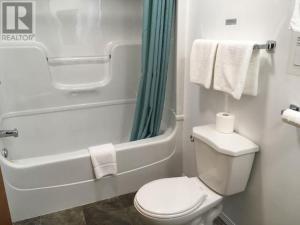 y baño con aseo y bañera con toallas. en Northside Motel, en Vermilion Bay