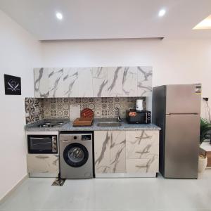 eine Küche mit einem Kühlschrank, einer Waschmaschine und einem Trockner in der Unterkunft SHL Hurghada Airport Aparthotel - By SAHLHOMES in Hurghada