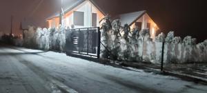 a fence covered in snow in front of a house at Villa Ensari Jezerc in Ferizaj