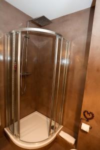 a shower with a glass door in a bathroom at Hôtel Restaurant Le Verger des Châteaux, The Originals Relais in Dieffenthal