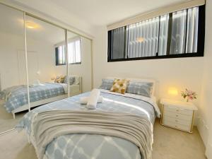 ein Schlafzimmer mit einem großen Bett und einem Spiegel in der Unterkunft A Cozy 2B2B Apartment near Airport & Train Station in Sydney