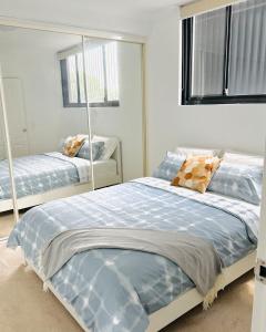 ein Schlafzimmer mit zwei Betten und einem Spiegel in der Unterkunft A Cozy 2B2B Apartment near Airport & Train Station in Sydney