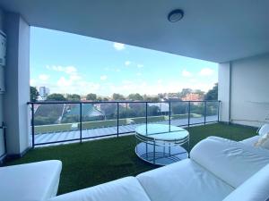 einen Balkon mit einem weißen Sofa und einem Tisch in der Unterkunft A Cozy 2B2B Apartment near Airport & Train Station in Sydney