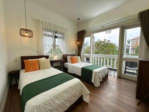 a bedroom with two beds and a balcony at Fullhouse Hoian in Hoi An
