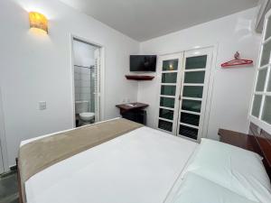 a white bedroom with a bed and a tv at Pousada Promessa Amanay antigamente Ubatuba Guest House in Ubatuba +60 photos
