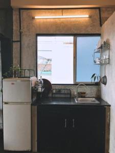 Il comprend une cuisine équipée d'un réfrigérateur, d'un évier et d'une fenêtre. dans l'établissement Nhà Saigon Homestay&Coffee, à Hô-Chi-Minh-Ville