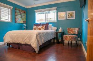 una camera da letto con pareti blu e un letto e una sedia di Seq Parks-House with Hot Tub Fire Pit Koi Pond Outdoor Kitchen a Visalia