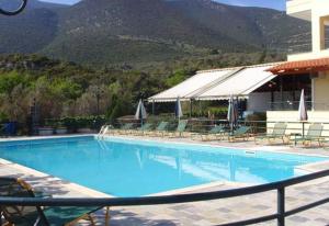 a large blue swimming pool with chairs and a building at Gefyra Rooms in Ancient Epidauros