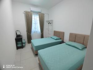 two beds in a small room with a window at Mars Homestay in Alor Setar