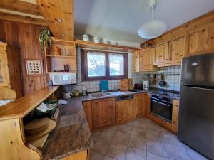 une cuisine avec des armoires en bois et un réfrigérateur en acier inoxydable dans l'établissement Chalet spacieux avec cheminée et salle de cinéma à Montgenèvre - FR-1-266-242, à Montgenèvre 11 autres photos