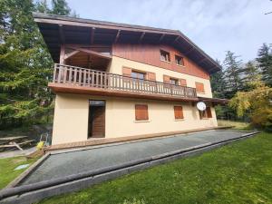 une maison avec un balcon au-dessus d'une cour dans l'établissement Chalet spacieux avec cheminée et salle de cinéma à Montgenèvre - FR-1-266-242, à Montgenèvre