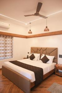a bedroom with a large bed with a ceiling fan at Flower Hill Cottage in Varkala
