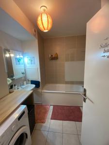 ein Badezimmer mit einer Badewanne, einem Waschbecken und einer Waschmaschine in der Unterkunft Appartement meublé et cosy in Gennevilliers