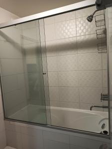 Apartment in La Paz #07 في لاباز: باب دش زجاجي في حمام مع حوض استحمام +49 صورة