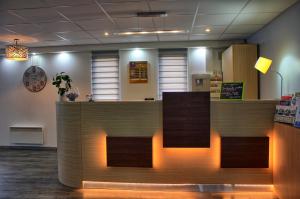 a lobby with a reception counter with lights at Contact Hotel Restaurant La Chaumière Les Mureaux-Flins in Les Mureaux