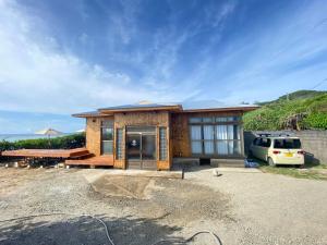 a small house with a car parked in front of it at Tamari House, a mansion with coral islands and natural pools in Amami