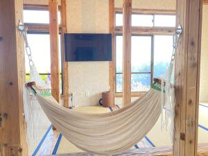 a hammock hanging in a room with windows at Tamari House, a mansion with coral islands and natural pools in Amami