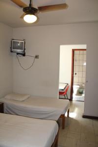 a room with two beds and a tv on the wall at Hotel Aquarius in Coronel Fabriciano