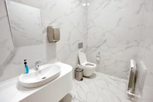 a white bathroom with a sink and a toilet at Qo'noq Tashkent Airport Hotel Sleep Lounge & Showers, Terminal 2 - TRANSIT ONLY in Tashkent